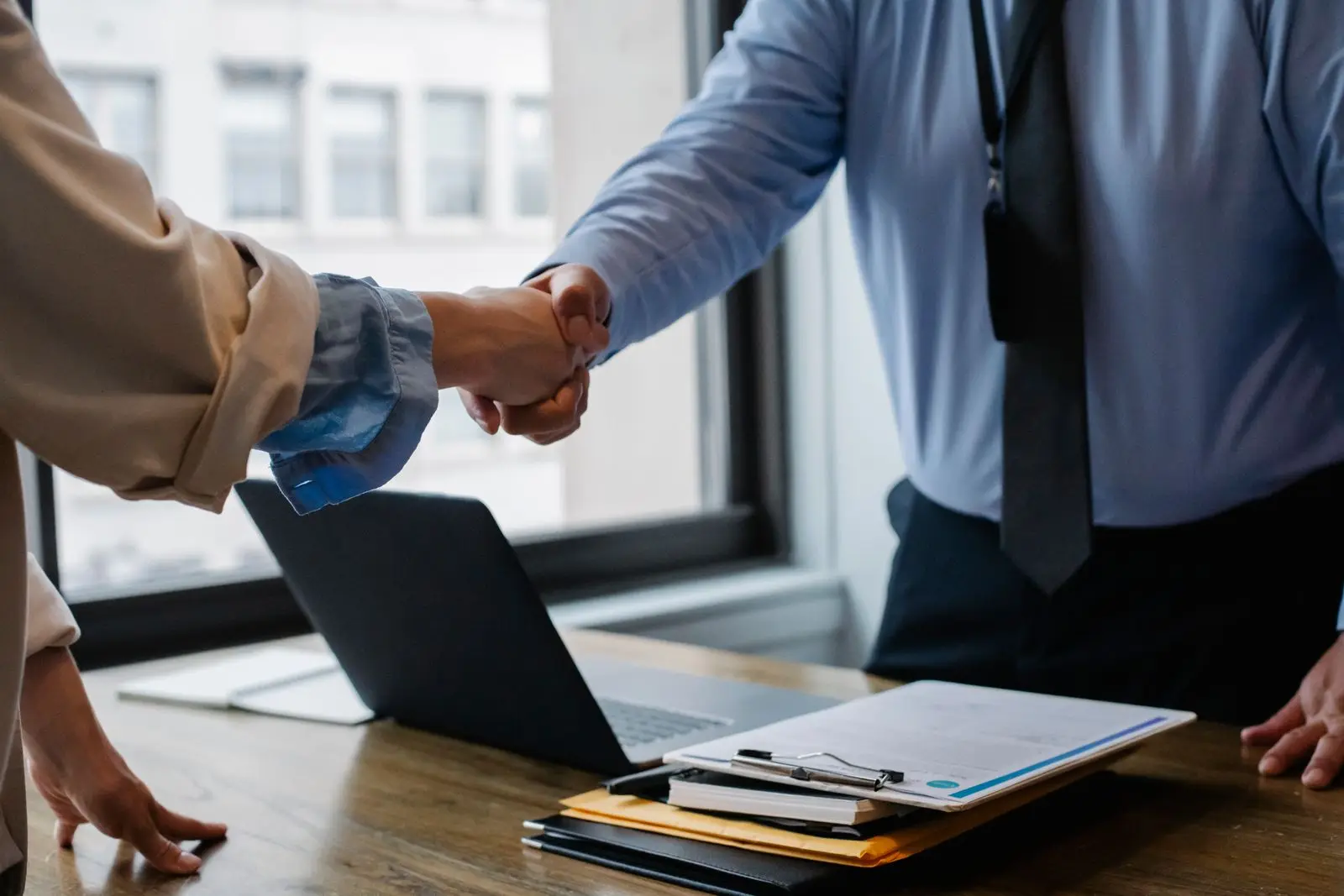 Two professionals shaking hands across a meeting desk