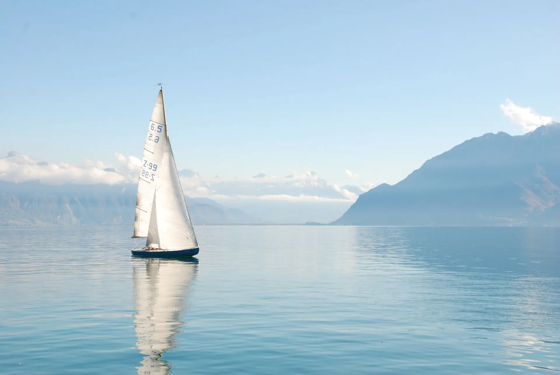 A single sailboat on calm water beneath open sky